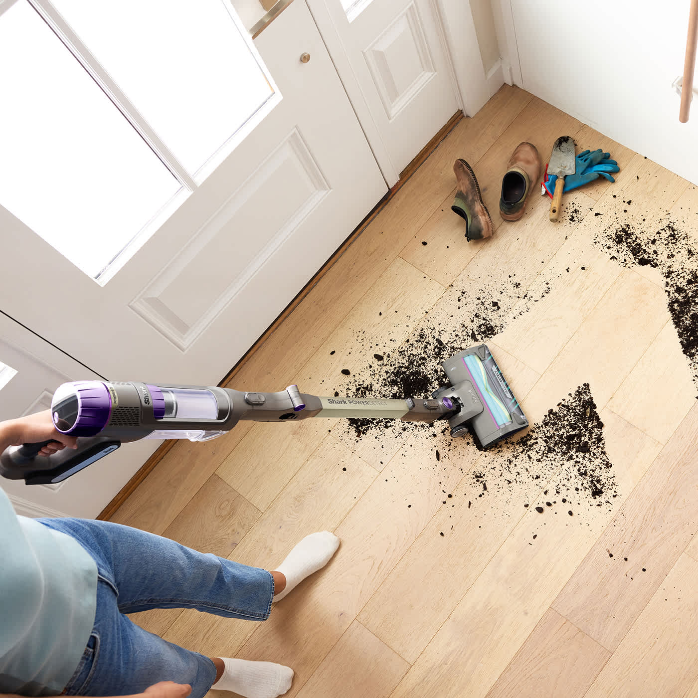 Woman cleaning up mud in the hallway using the PowerDetect cordless vacuum cleaner